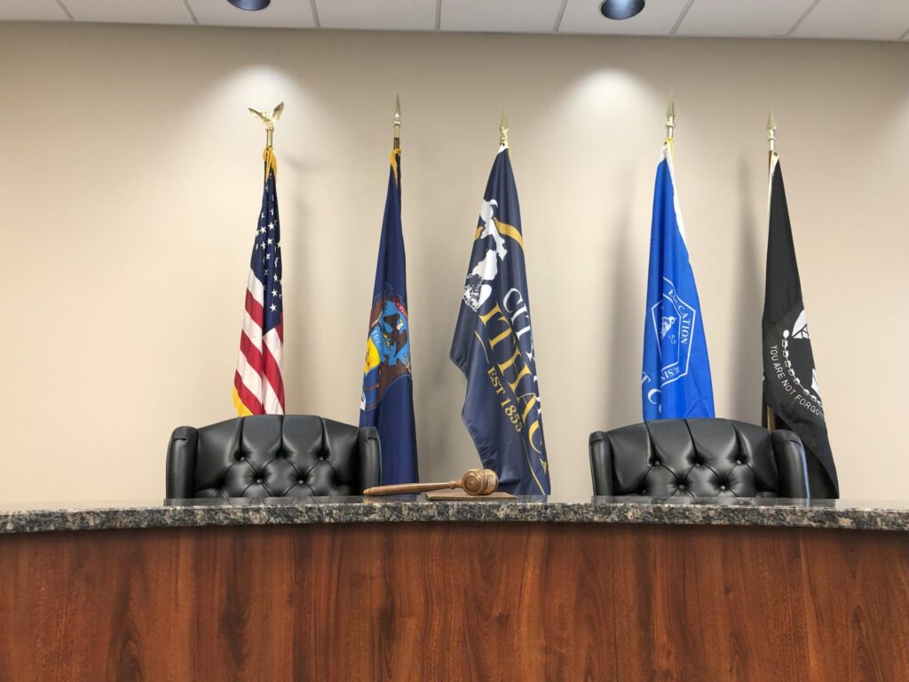 Judge&#039;s bench with flags and gavel in courtroom.