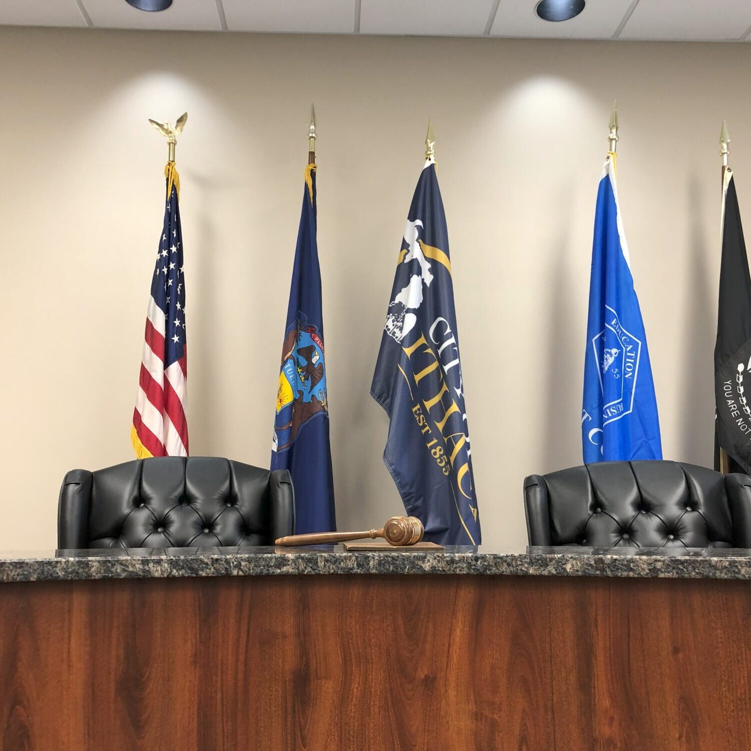 Judge's bench with flags and gavel in courtroom.